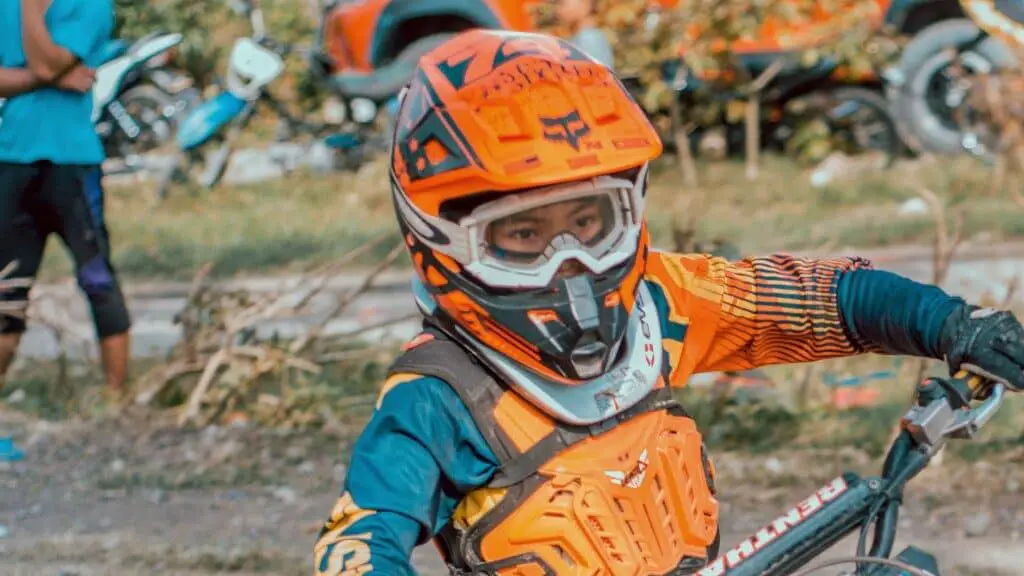 Boy wearing motorcross helmet, boy wearing orange motorcross helmet