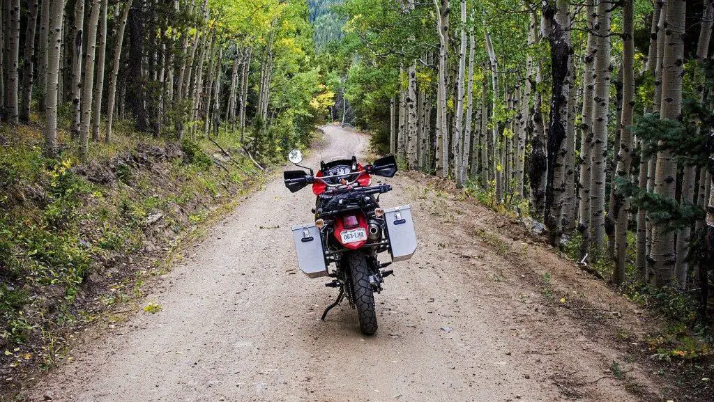 Adventure bike on forest road, adventure bike with metal panniers, Red adventure bike in forest