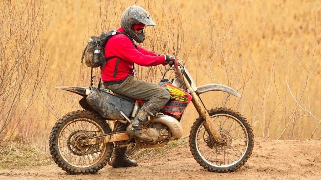 man with rucksack on dual sports motorcycle, Dual sports motorcycle with knobbly tires